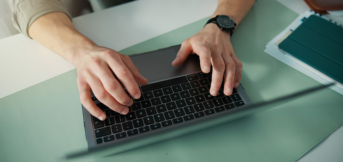 Manos tecleando sobre un ordenador portátil.