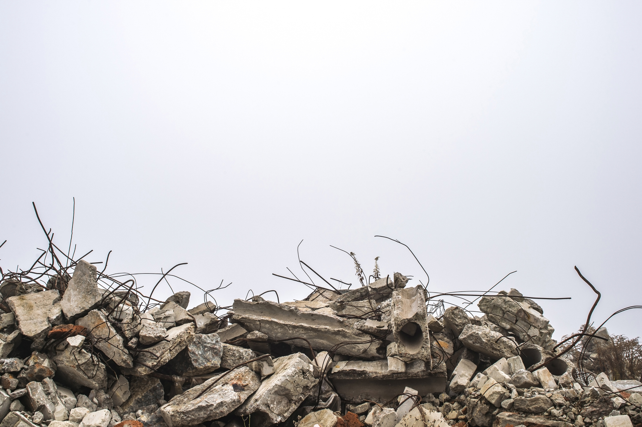 La armadura que se pega de montones de escombros de ladrillo, piedra y escombros de hormigón contra el cielo en una neblina