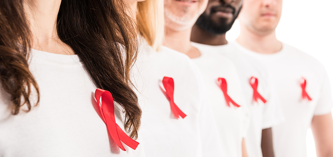 Varias personas con un lazo rojo en el pecho