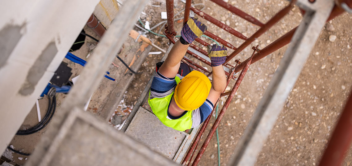 Persona obrera bajando escaleras de andamios.