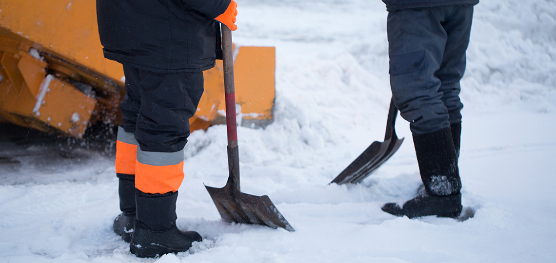 Dos personas trabajadoras recogiendo nieve con palas